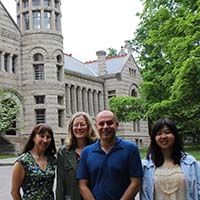 Photo of four people standing in front of Maxwell Hall